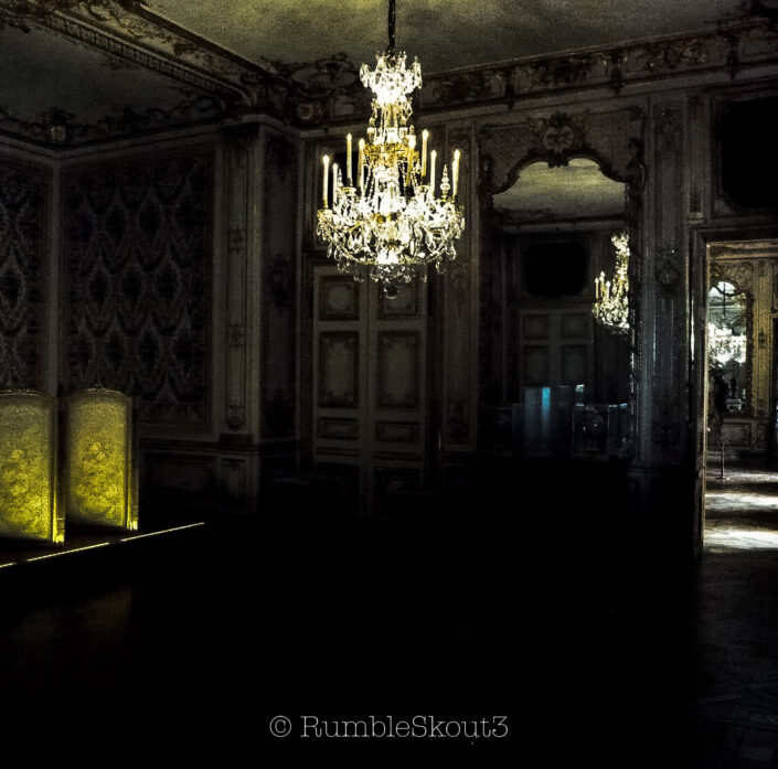 In the State Apartment, a historic chandelier is reflected upon by a french historical mirror inside the creation of Jules Hardouin-Mansart and Louis Le Vau masterpiece french baroque architect Château de Versailles. A Gravitational Singularity A historic chandelier is reflected upon by a french historical mirror inside the State Apartment of a french-baroque-architect masterpiece.