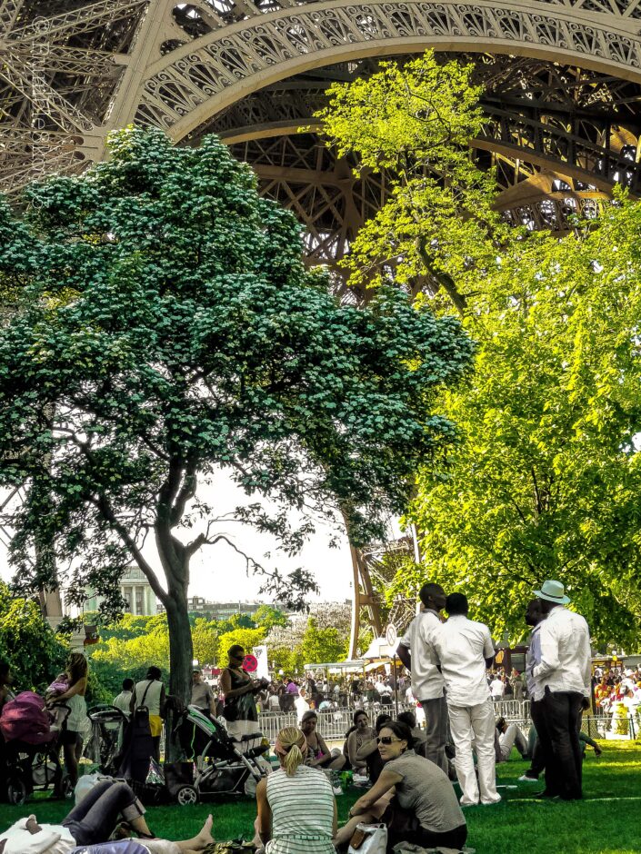 Right below a world famous french monument, a gathering of people near and below Eiffel Tower, 7th arrondissement de Paris on Champs de Mars. An Eiffel Conversation