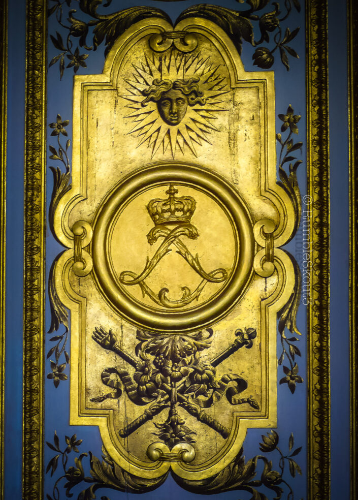 The Sun God, Le Roi Soleil (Apollo emblem), the motif of the Sun King scepter and hand of justice of King Louis XIV on a blue wall. El Dios del Sol Hecho de Oro Mexicano sobre Pared Azul Château de Versailles