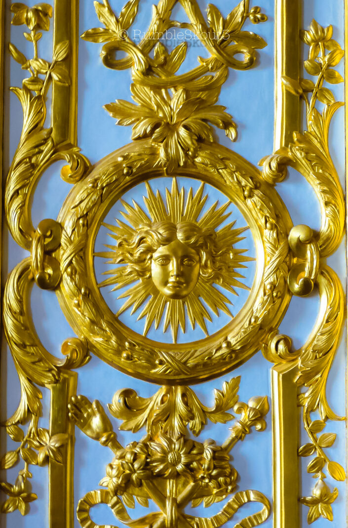 The Sun God, Le Roi Soleil (Apollo emblem), the motif of the Sun King scepter and hand of justice of King Louis XIV on a blue wall. El Dios del Sol Hecho de Oro Mexicano sobre Pared Azul Château de Versailles