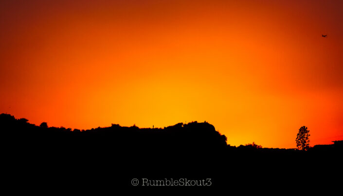 A plane and people on the rocks enjoy an Alta California Sunset afterglow from Runyon Canyon Park in the Hollywood Hills. leica