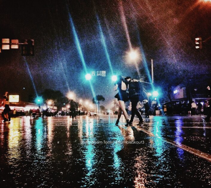 A couple going home in Romantic LA Rain at the intersection of Santa Monica Blvd & N Robertson Blvd at the end of the Halloween Carnaval in West Hollywood. (Los Angeles Street Photography)