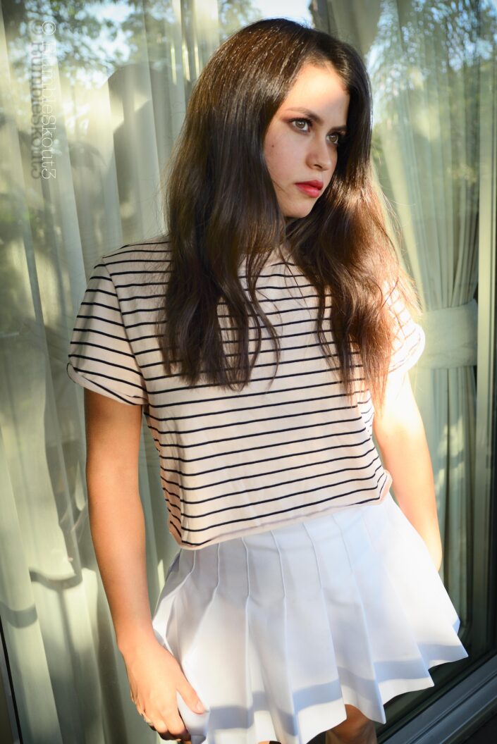 An Indigenous Mexican Nikon fine art Natural Light Fashion Photography session of an aspiring Hilfiger Fashion Model in women's striped top and pleated tennis skirt with amber-eyes-American beauty fashion model. Réflexion Avant-Gardiste Tennis skirt fashion