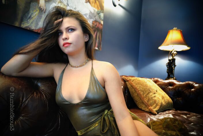 An American woman portrait of a Space Age Love Song, Playing Around on Leather, in a bodysuit sheer dress on a leather chesterfield sofa in West Hollywood.